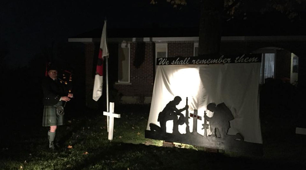 A bagpiper plays in front of a backlt Remembrance Day display in front of Dennis Burton's home on Flewellyn Road.