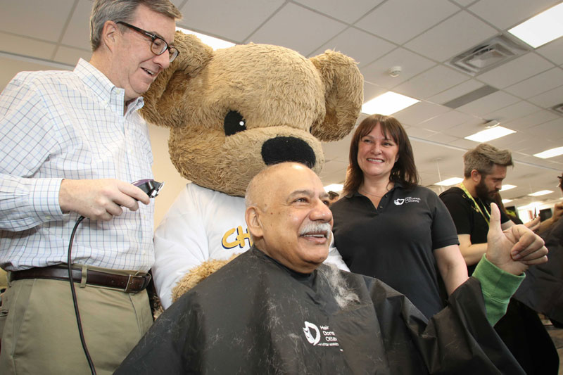 Congrats to Helene Hutchings for organizing another successful Hair Donation Ottawa event today to support cancer research. With donations still coming in, the event will raise at least $90,000. Hutchings is pictured above with the CHEO Bear, watching as Ottawa Mayor Jim Watson shaves Stittsville councillor Shad Qadri's head. Photo by Barry Gray.